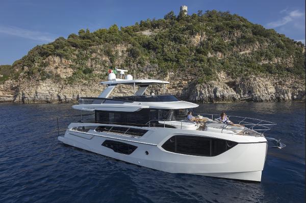 Slide: The Image of 2024 Absolute Navetta 64 yacht cruising near a rocky coastline. - 1