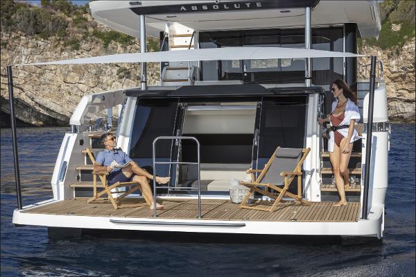 Slide: The Image of 2024 Absolute Navetta 64 yacht with people relaxing on the deck in a scenic coastal area. - 3