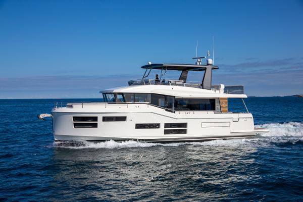 Slide: The Image of 2025 Beneteau Grand Trawler 62 cruising on open water under clear blue skies. - 1