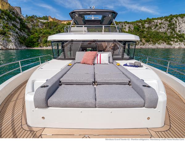 Slide: The Image of 2025 Beneteau Grand Trawler 62 yacht with sunbed, docked in scenic coastal waters. - 18