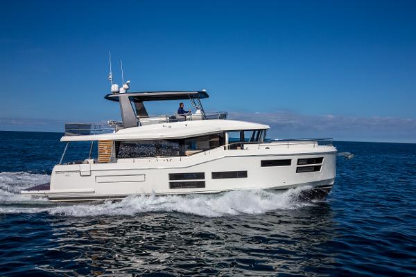 Slide: The Image of 2025 Beneteau Grand Trawler 62 cruising on open sea under clear blue sky. - 2