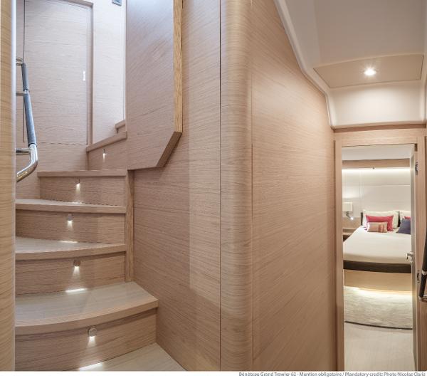 Slide: The Image of Interior of 2025 Beneteau Grand Trawler 62, featuring elegant wooden staircase and cozy bedroom. - 27