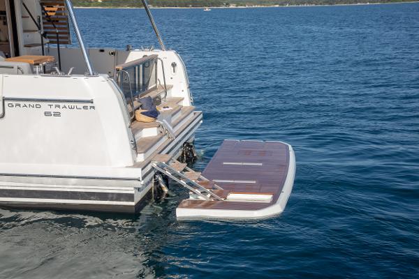 Slide: The Image of 2025 Beneteau Grand Trawler 62 yacht with extended swim platform on calm water. - 3