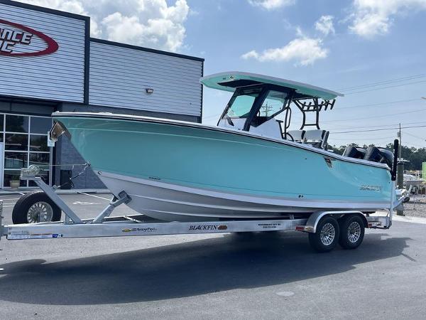 Slide: The Image of 2024 Blackfin 272 CC boat on a trailer, parked outside a dealership. - 2