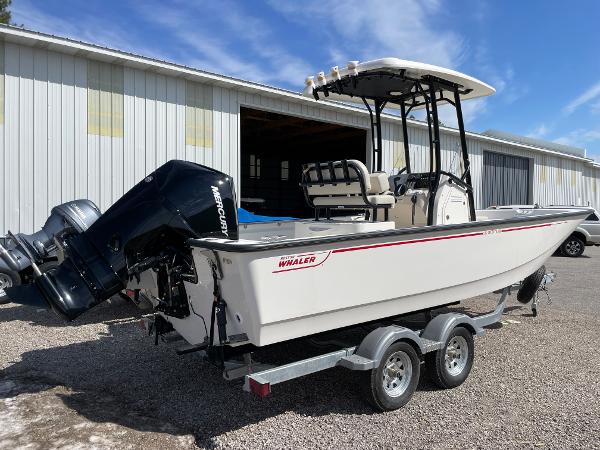 Slide: The Image of 2023 Boston Whaler 210 Montauk boat on a trailer, parked outside a warehouse. - 6