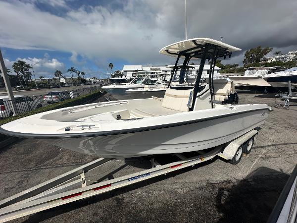 Slide: The Image of 2024 Boston Whaler 220 Dauntless boat on a trailer in a marina. - 1