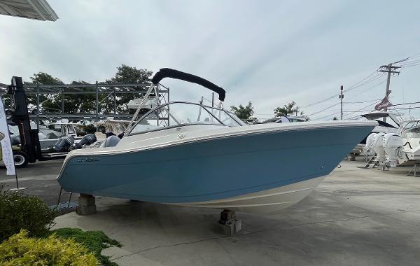 Slide: The Image of 2024 Cobia 220 Dual Console boat on display in a marina. - 0