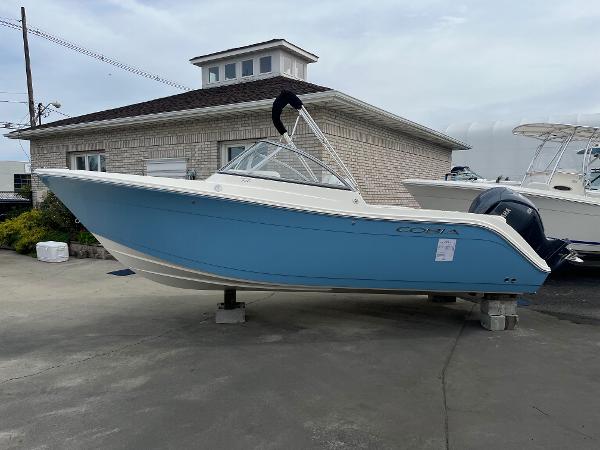 Slide: The Image of 2024 Cobia 220 Dual Console boat in light blue, displayed on a stand. - 1