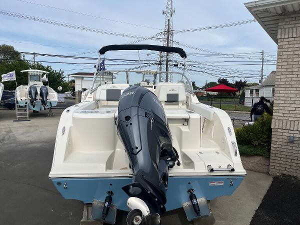 Slide: The Image of 2024 Cobia 220 Dual Console boat with outboard motor, rear view. - 2