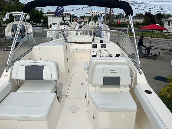 Slide: The Image of 2024 Cobia 220 Dual Console boat with seating and steering wheel, docked at marina. - 4