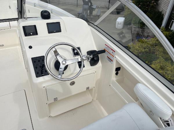 Slide: The Image of 2024 Cobia 220 Dual Console boat helm with steering wheel and control panel. - 5