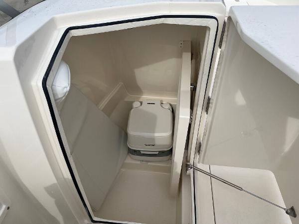 Slide: The Image of 2024 Cobia 220 Dual Console boat interior with portable toilet. - 6