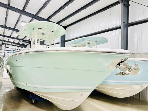 Slide: The Image of 2024 Cobia 262 CC boat in showroom, mint green hull, sleek design. - 0