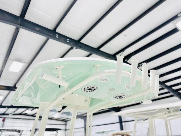 Slide: The Image of 2024 Cobia 262 CC boat top with rod holders and speakers in a showroom. - 15