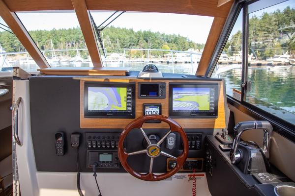 Slide: The Image of 2024 Cutwater 32 CB boat helm with dual navigation screens and wooden steering wheel. - 1