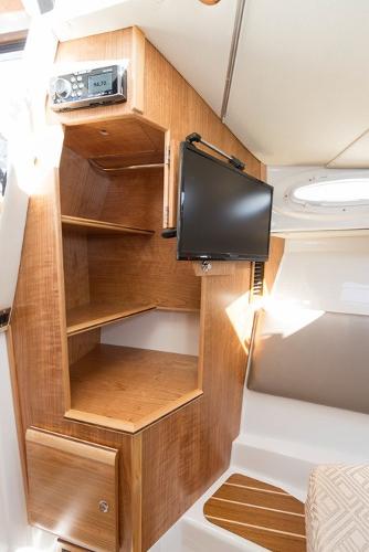 Slide: The Image of 2024 Cutwater 32 CB cabin interior with TV and wooden shelves. - 10