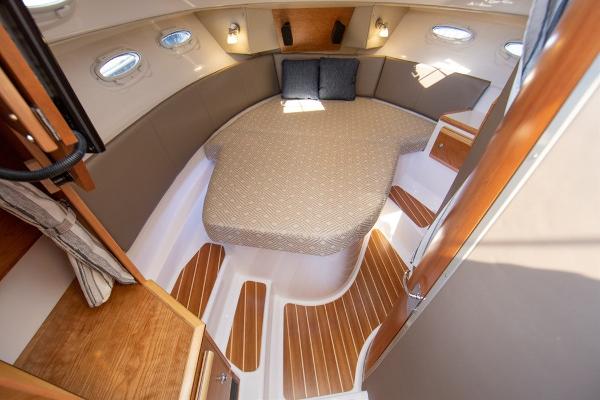 Slide: The Image of 2024 Cutwater 32 CB cabin interior with bed, wooden accents, and portholes. - 3
