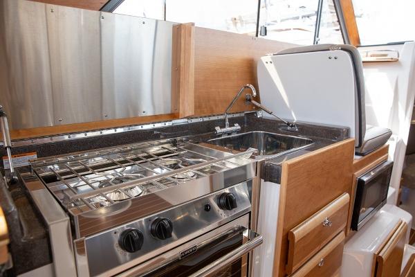Slide: The Image of 2024 Cutwater 32 CB boat kitchen with stainless steel stove and sink. - 5