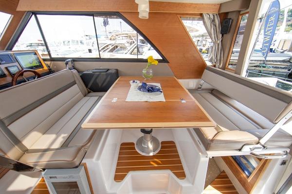 Slide: The Image of 2024 Cutwater 32 CB interior dining area with wood table and cushioned seating. - 8
