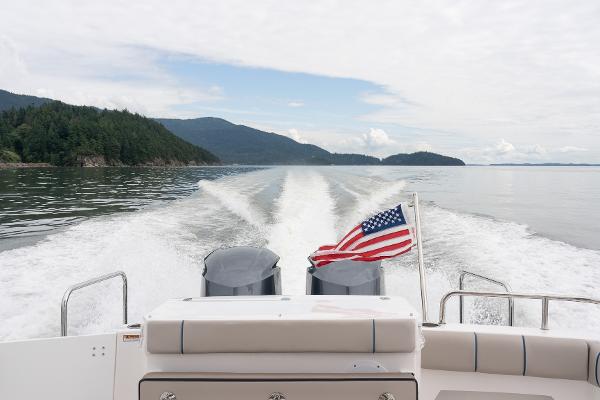 Slide: The Image of 2021 Cutwater 32 Command Bridge cruising with American flag, scenic water and forested hills. - 17