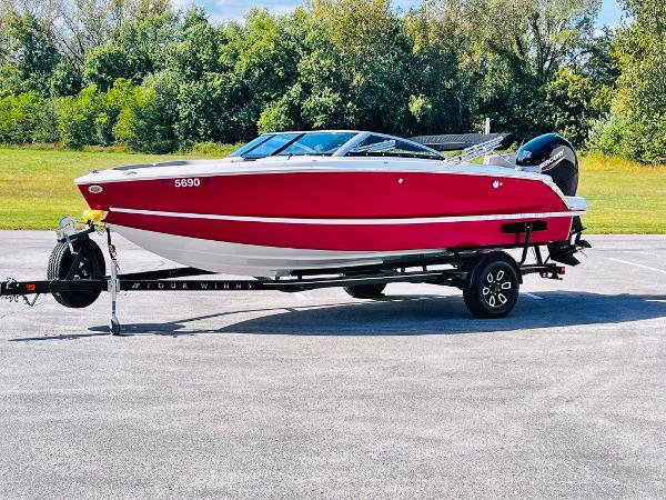 Slide: The Image of 2023 Four Winns H1 OB boat on trailer, red and white, parked outdoors. - 0