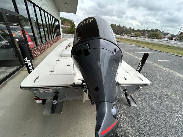 Slide: The Image of 2024 Hewes Redfisher 18 boat with outboard motor, displayed outdoors. - 16