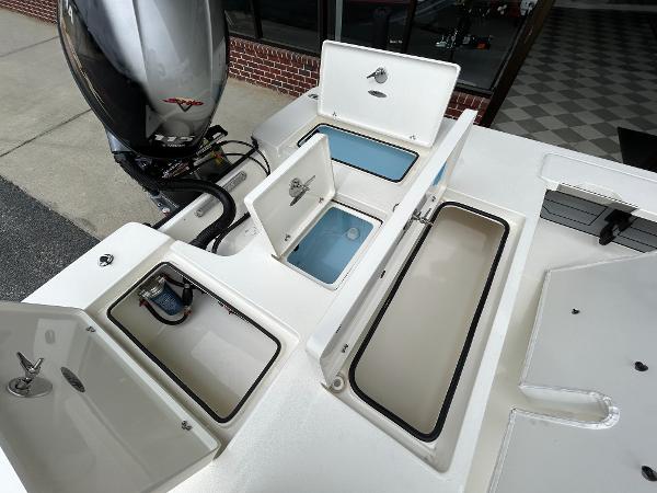 Slide: The Image of 2024 Hewes Redfisher 18 boat with open storage compartments and outboard motor. - 21