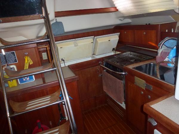 Slide: The Image of 2001 Hunter 420 Passage yacht kitchen with wooden cabinetry, stainless steel sink, and stove. - 20
