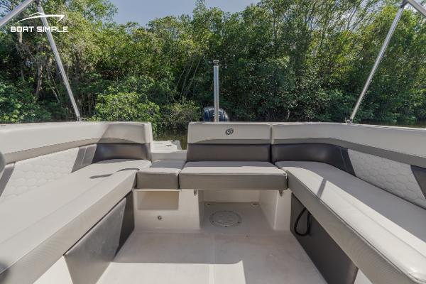 Slide: The Image of 2022 Hurricane 217 SD boat interior with spacious seating and lush greenery background. - 11