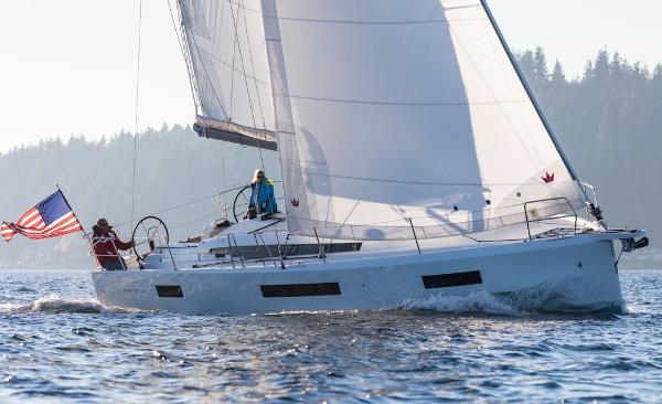 Slide: The Image of 2025 Jeanneau Sun Odyssey 440 sailing on open water with American flag. - 0