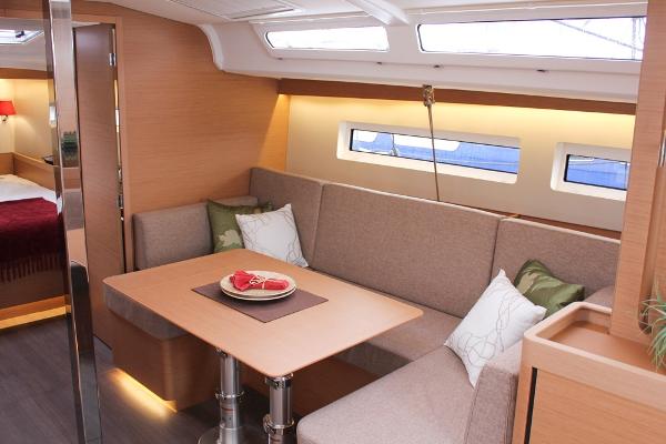 Slide: The Image of Interior of 2025 Jeanneau Sun Odyssey 440 yacht, featuring a cozy dining area with cushions. - 39