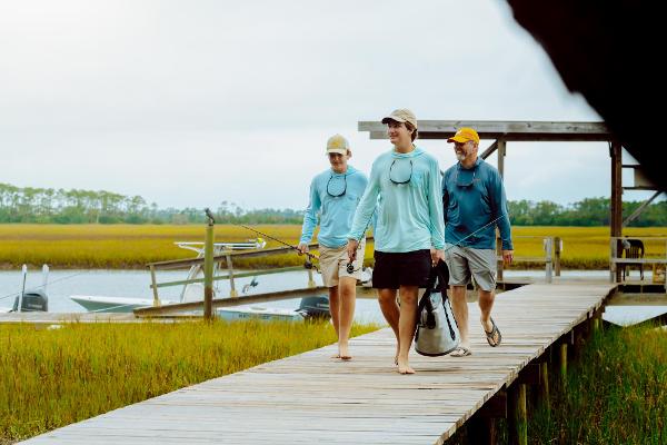 Slide: The Image of Three people walking on a dock near a 2023 Key West 250 Bay Reef boat. - 38