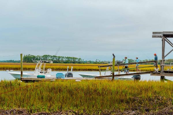 Slide: The Image of 2025 Key West 250 Bay Reef boat docked in marshland with people walking on pier. - 48