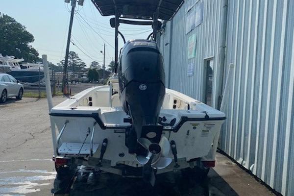 Slide: The Image of 2011 Mako 2201 Inshore boat with outboard motor, parked near a metal building. - 2