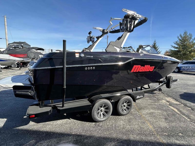 Slide: The Image of 2024 Malibu M220 boat on trailer, black exterior, parked outdoors. - 3