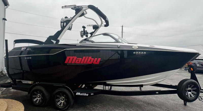 Slide: The Image of 2024 Malibu M220 boat on trailer, sleek black design with red logo. - 6