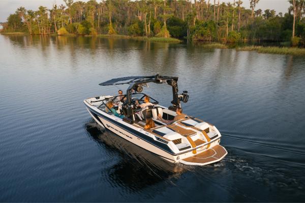 Slide: The Image of 2023 Nautique Super Air GS22E boat cruising on a serene lake with passengers. - 1