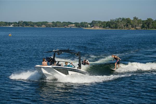 Slide: The Image of 2023 Nautique Super Air GS22E towing wakeboarders on a sunny lake. - 22