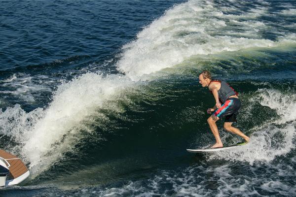 Slide: The Image of Man wakesurfing behind 2023 Nautique Super Air GS22E boat on a lake. - 23