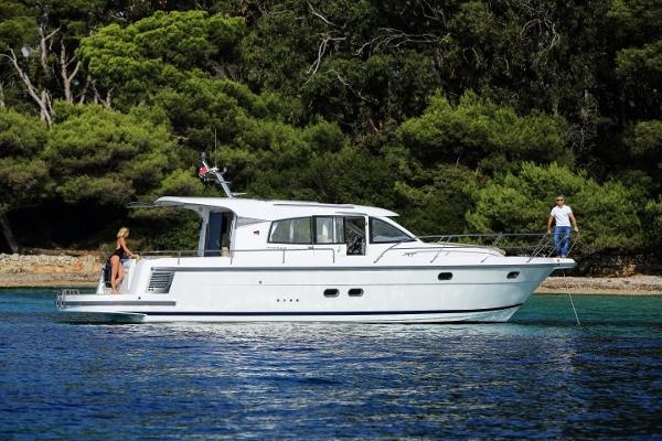 Slide: The Image of 2025 Nimbus 405 Coupé yacht cruising near a forested shoreline. - 0