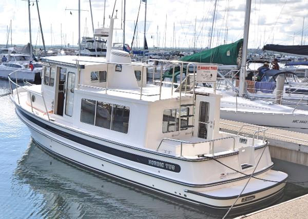 Slide: The Image of 2025 Nordic Tug 34 docked at a marina, surrounded by other boats. - 0
