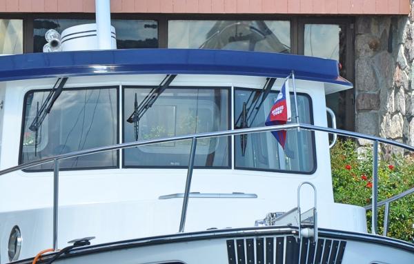 Slide: The Image of Nordic Tug 34 (2025) boat docked, front view with blue canopy and windows. - 9
