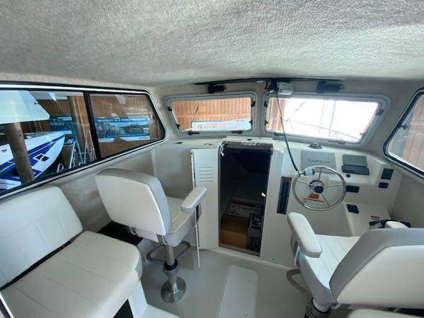 Slide: The Image of Interior of 2024 Parker 2520 XLD Sport Cabin boat with white seating and steering console. - 6