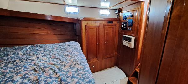 Slide: The Image of Cozy cabin interior of 1999 Rozema Boat Works Custom 42 with wooden paneling and floral bedding. - 12