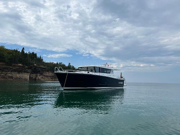 Slide: The Image of 2023 Sargo 45 boat cruising on calm waters near a rocky shoreline under a cloudy sky. - 26