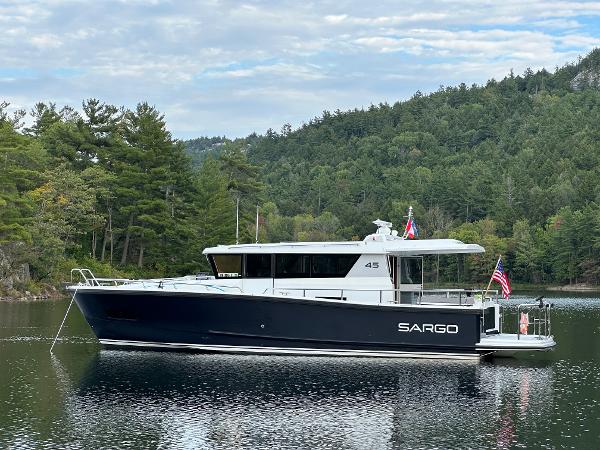 Slide: The Image of 2023 Sargo 45 boat on a serene lake with forested hills in the background. - 35
