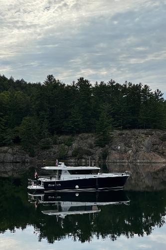 Slide: The Image of 2023 Sargo 45 boat on calm water with forested rocky shoreline. - 36