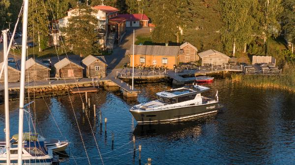 Slide: The Image of Sargo 45 Cat A 2025 boat docked at a scenic lakeside marina with rustic buildings. - 3