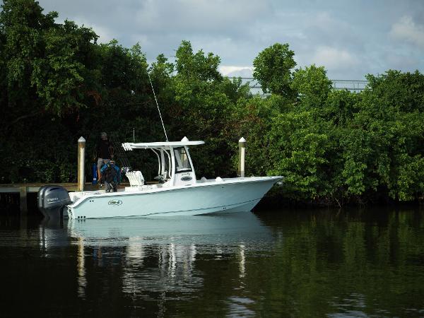 Slide: The Image of 2025 Sea Hunt Gamefish 25 boat docked by lush greenery. - 0
