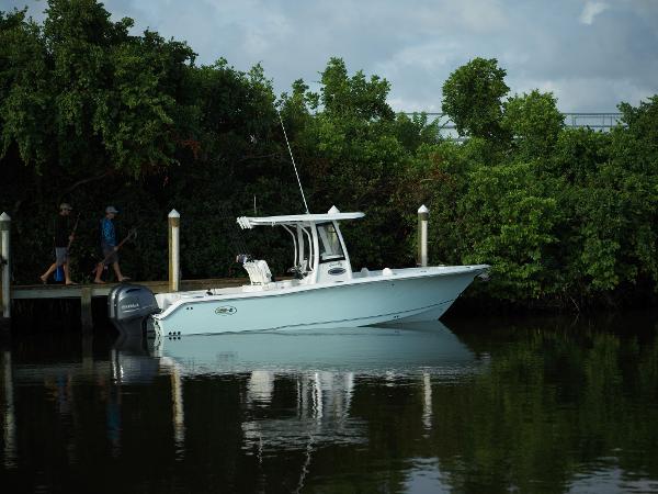 Slide: The Image of 2025 Sea Hunt Gamefish 25 boat docked by lush greenery. - 1